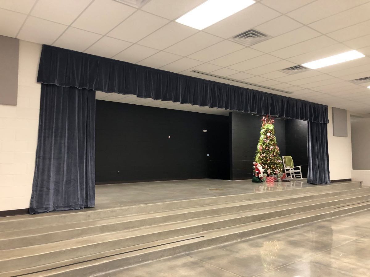 Empty stage with blue curtains and a lit Christmas tree on the right