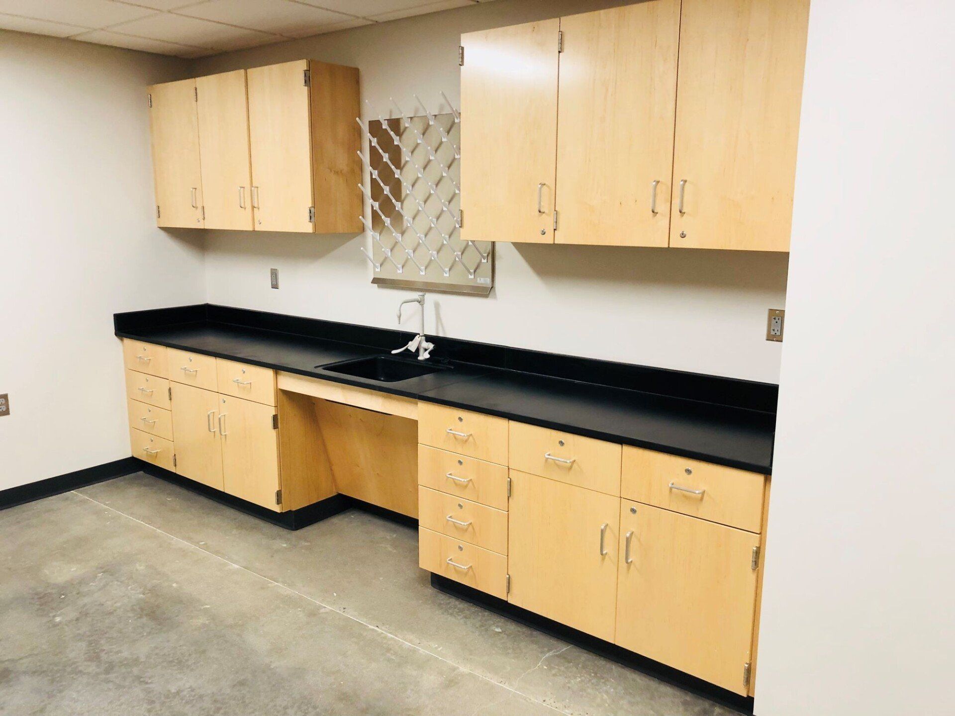 Empty room with light wood cabinets and black countertop along the wall