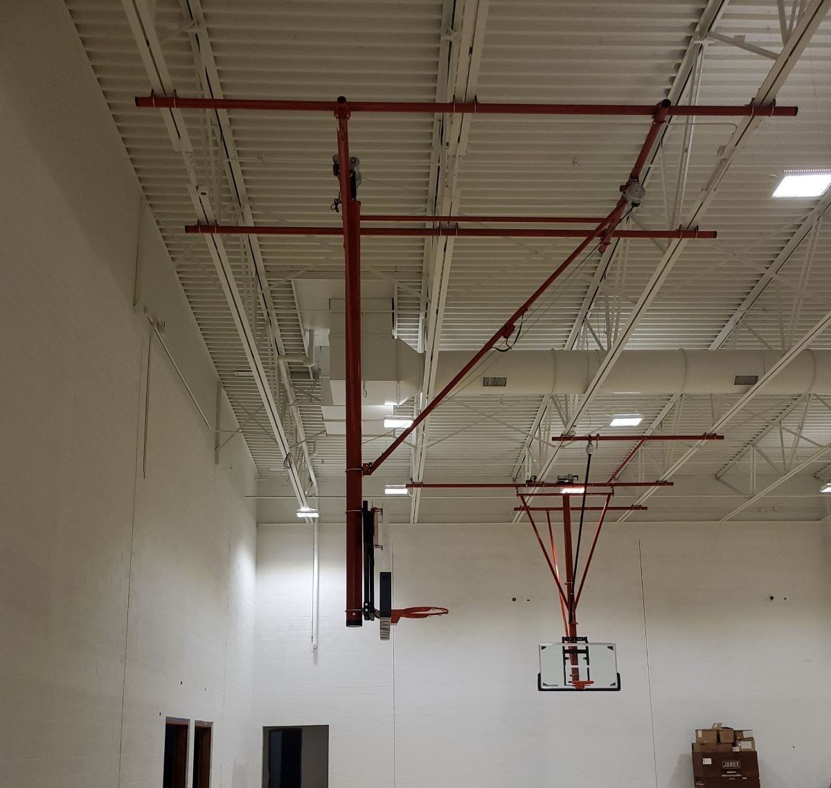 Red fire sprinkler pipes hanging from the ceiling in a large warehouse or industrial space