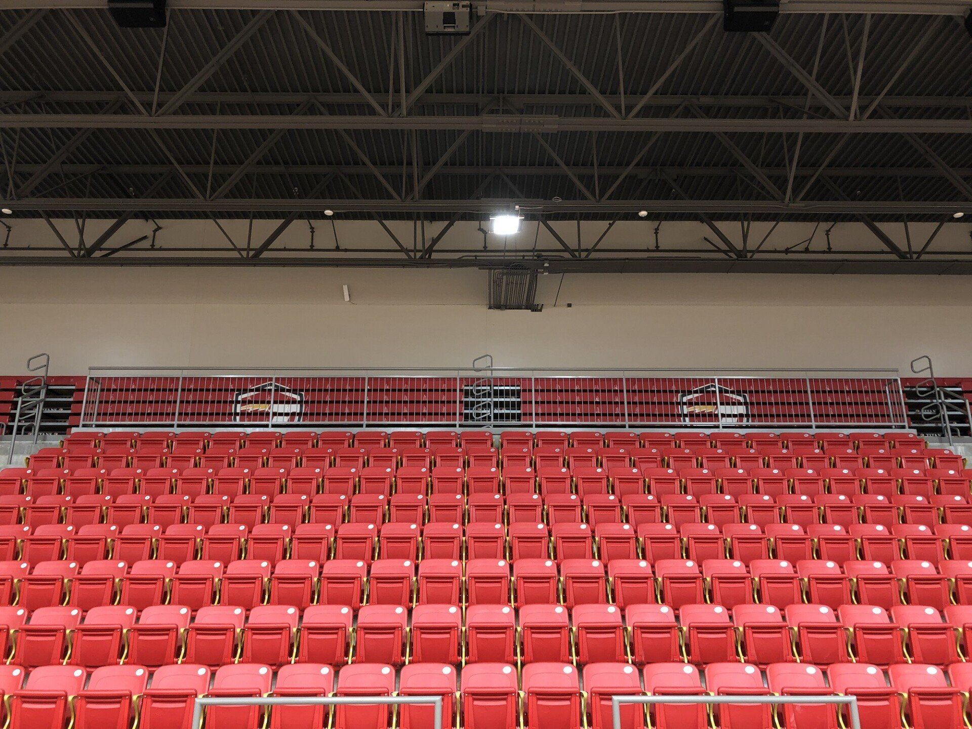 Empty red stadium seating under an indoor arena ceiling