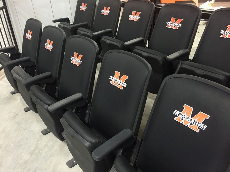 Rows of black stadium seats with orange-and-white logos in an indoor arena