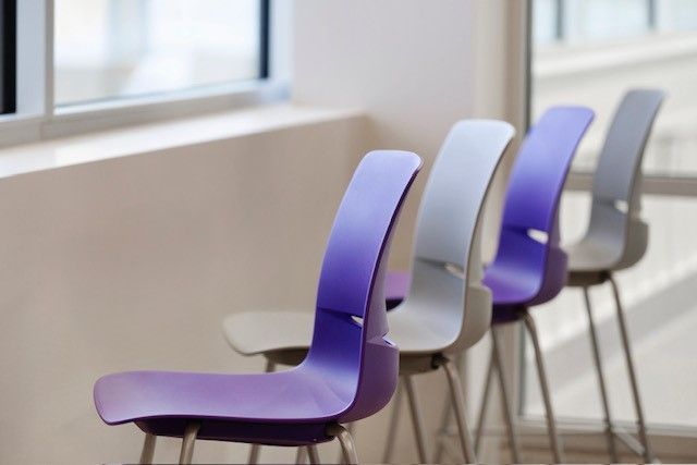 Row of modern purple and white chairs by a bright window in a minimalist room