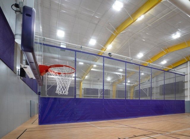 Indoor basketball court with hoop, blue walls, and a polished wooden floor
