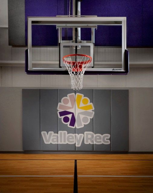 Indoor basketball hoop and backboard above a gym floor with ValleyRec logo on the wall.
