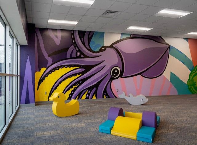 Colorful lobby with a purple octopus mural and bright yellow and teal seating