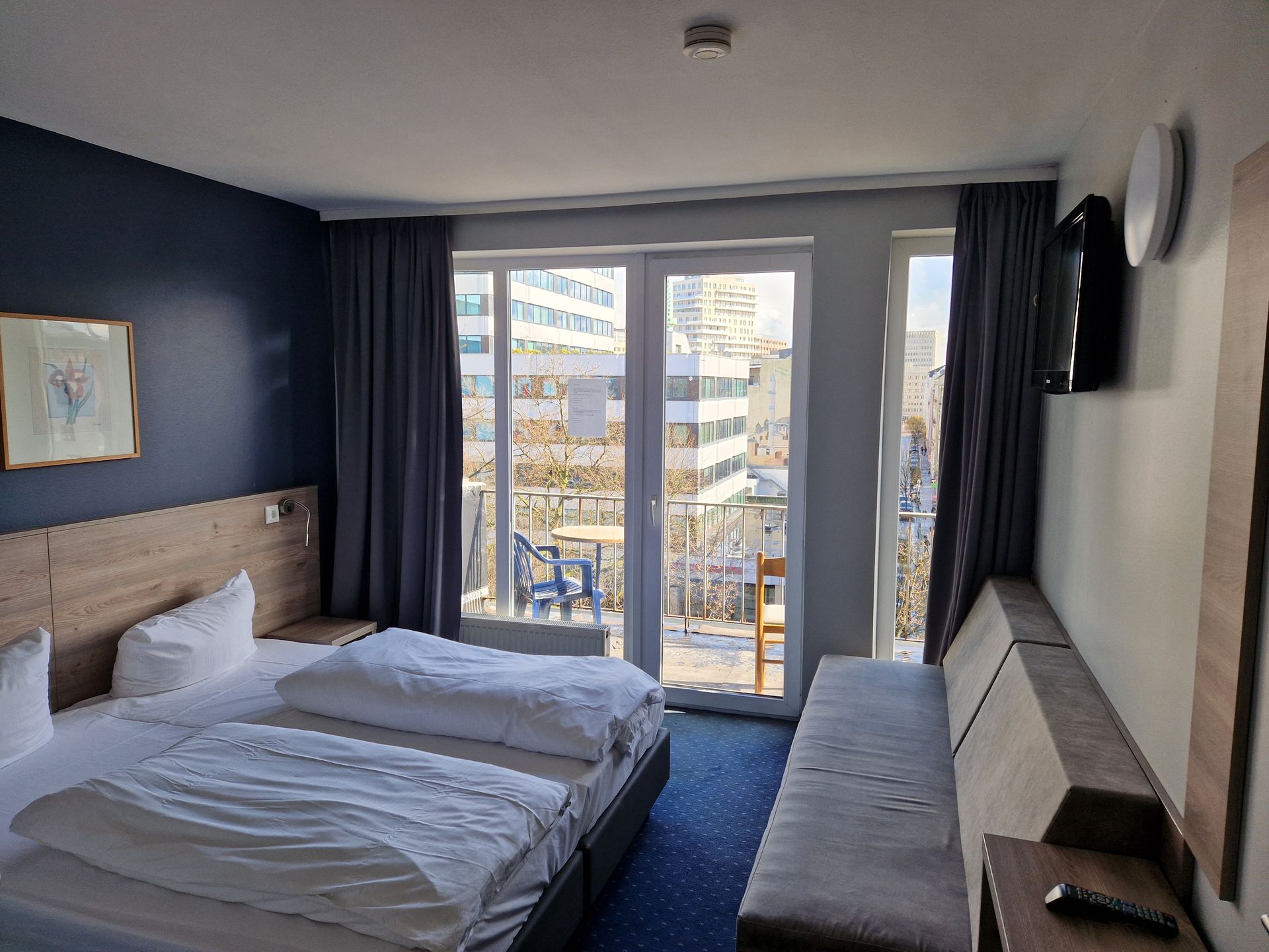 Ein Hotelzimmer mit zwei Betten, einer Couch und einem Fernseher.