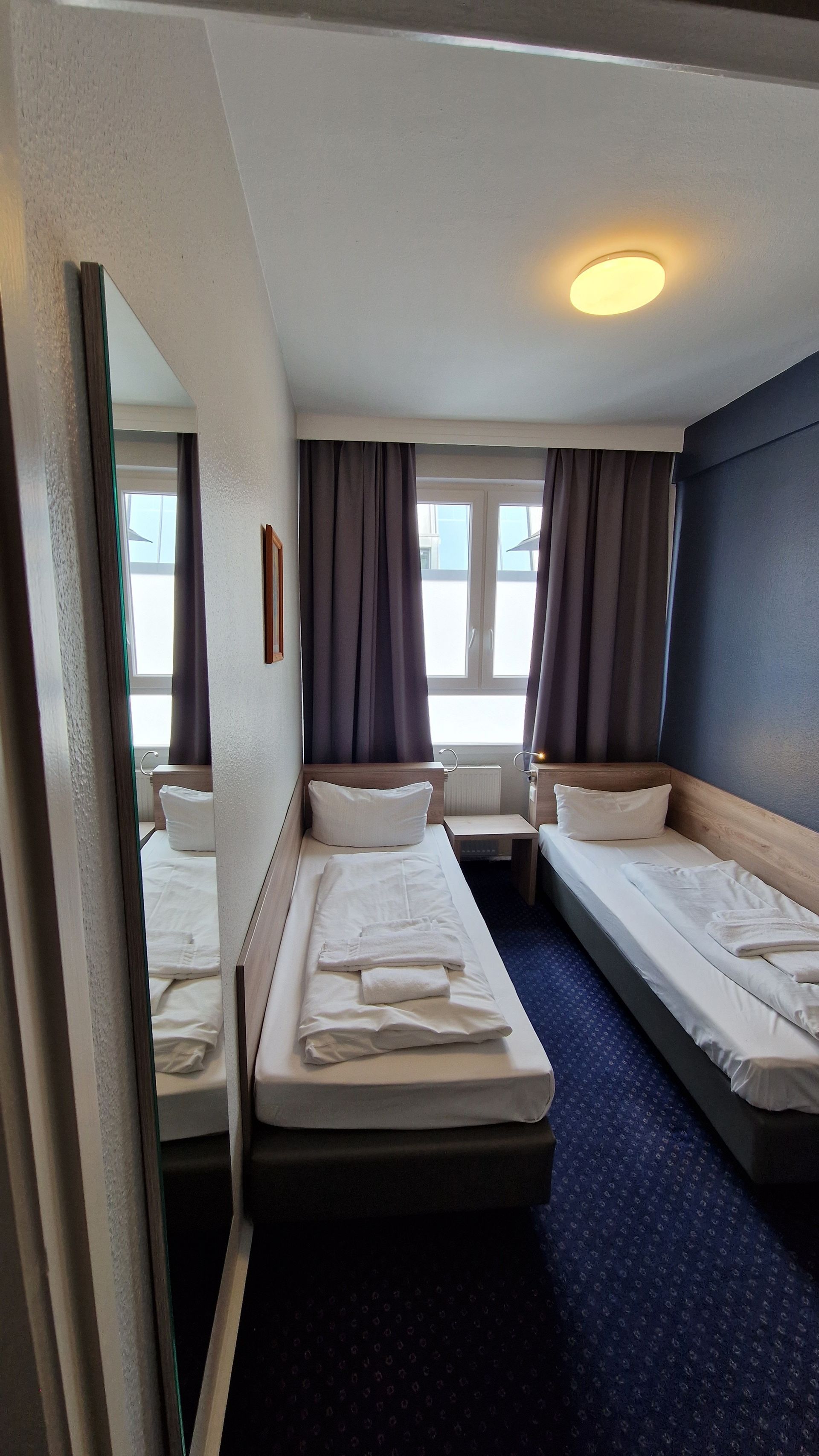 Ein Hotelzimmer mit zwei Betten und einem Spiegel.