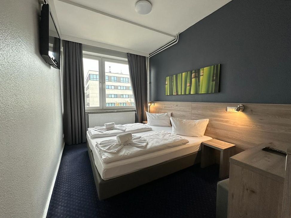 Ein Hotelzimmer mit zwei Betten und einem Fernseher an der Wand.