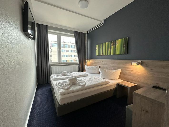 Ein Hotelzimmer mit zwei Betten und einem Fernseher an der Wand.