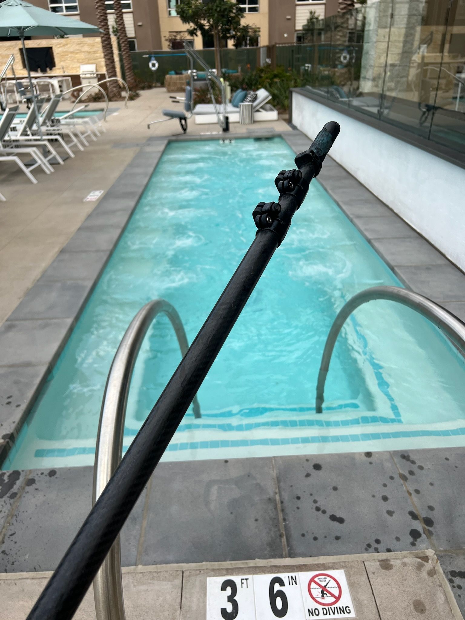 A person is standing next to a swimming pool with stairs leading to it.