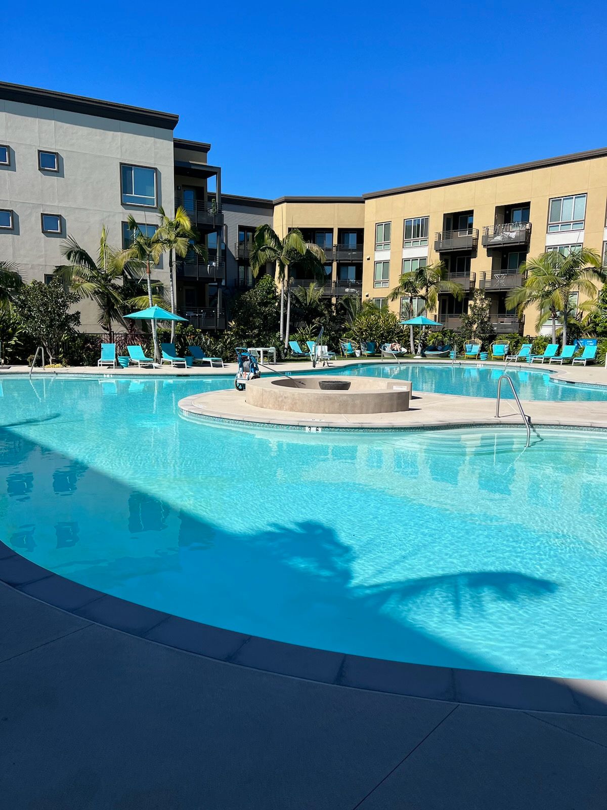 A large swimming pool surrounded by buildings and palm trees
