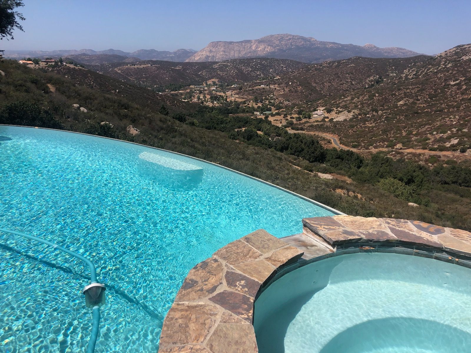 A swimming pool with mountains in the background and a hot tub