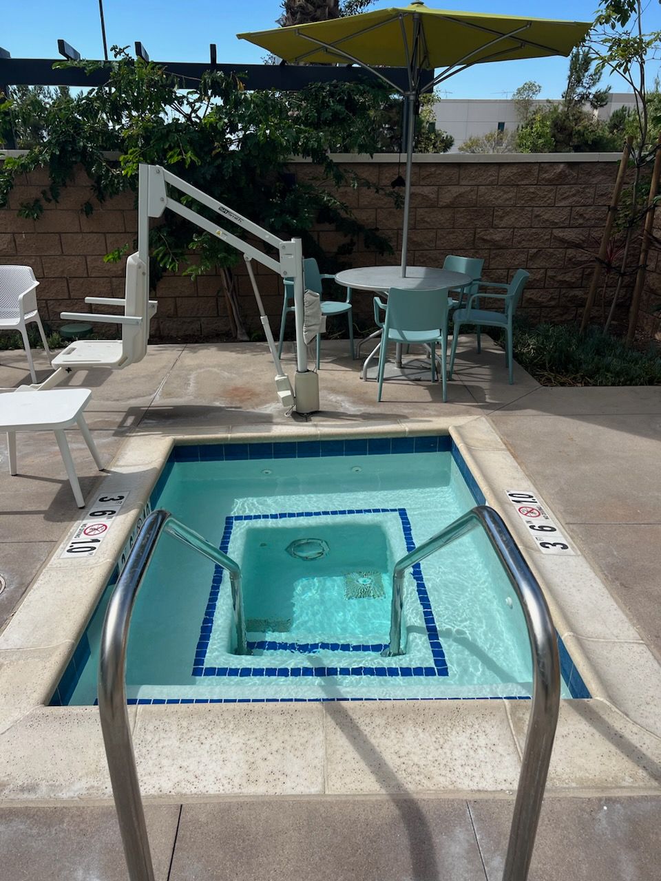 A swimming pool with stairs leading to it and a yellow umbrella