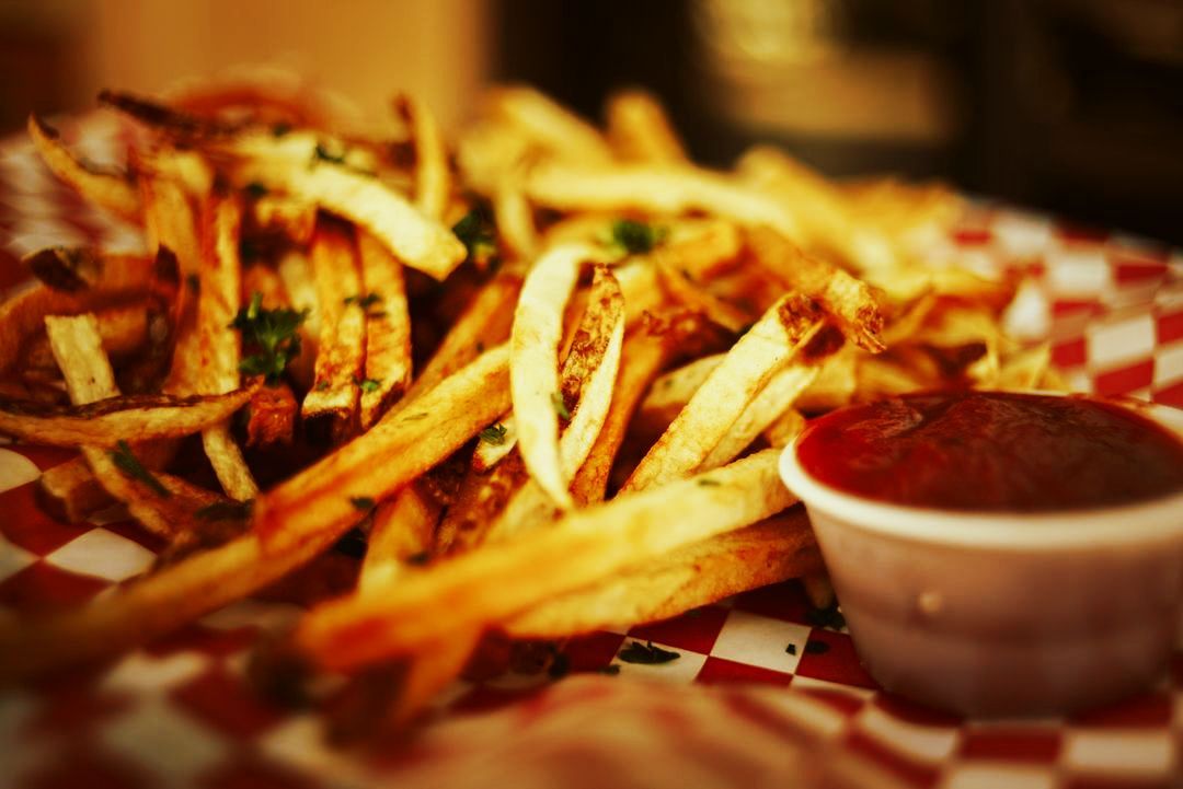 A plate of french fries with ketchup on a checkered table cloth