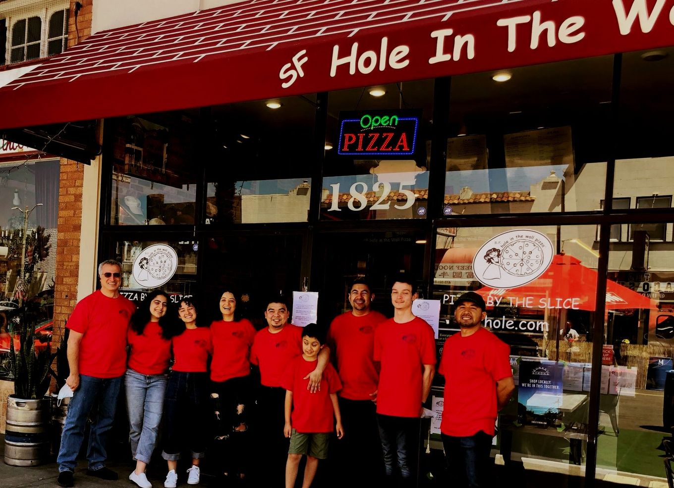 A group of people standing in front of a pizza restaurant