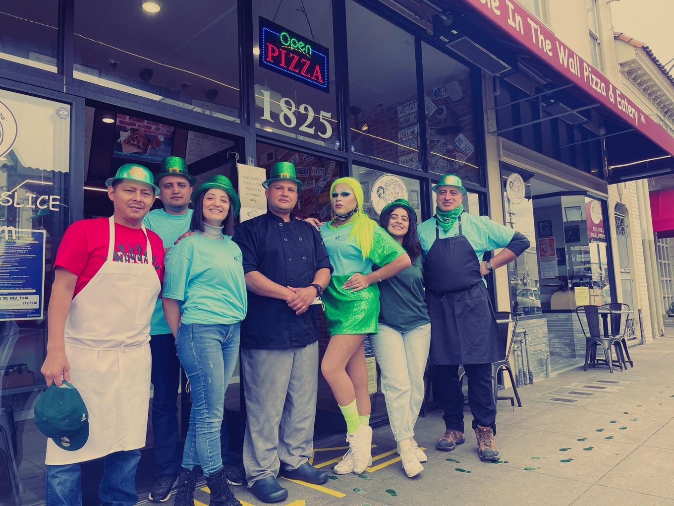 A group of people posing in front of a pizza shop