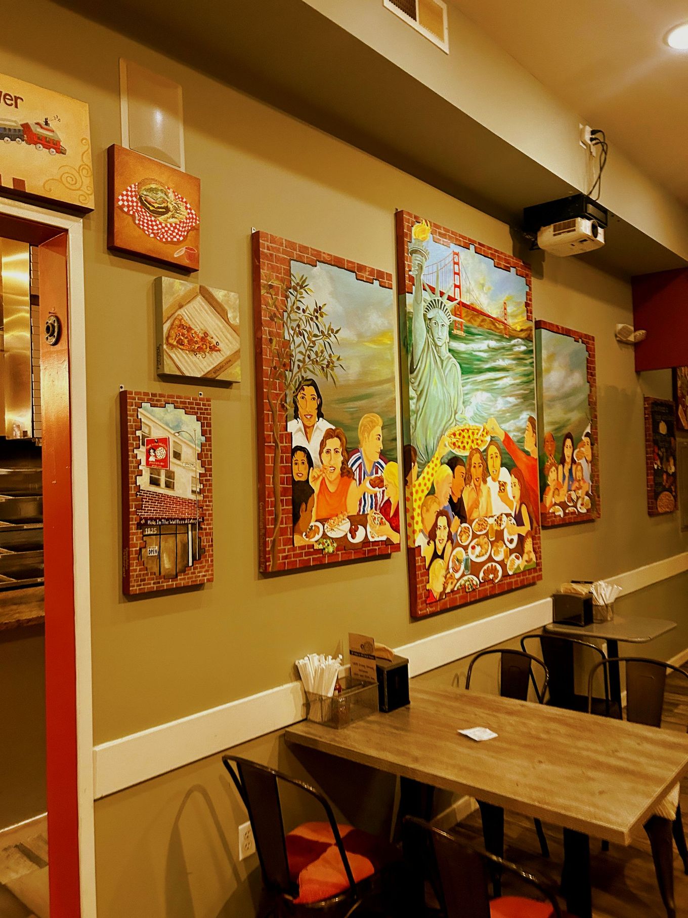 A restaurant with tables and chairs and paintings on the wall