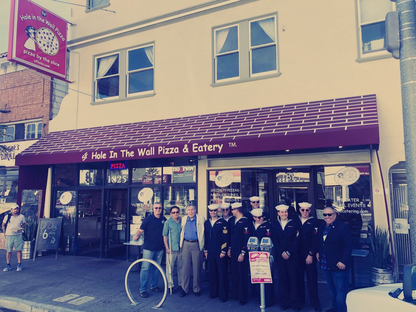 A group of men standing in front of a pizza restaurant