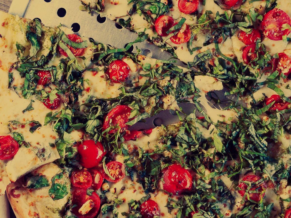 A pizza with tomatoes and spinach.