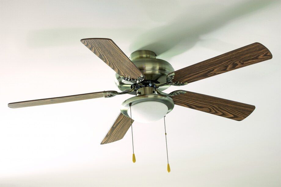 Ceiling fan with five wooden blades and a frosted light fixture, viewed from below