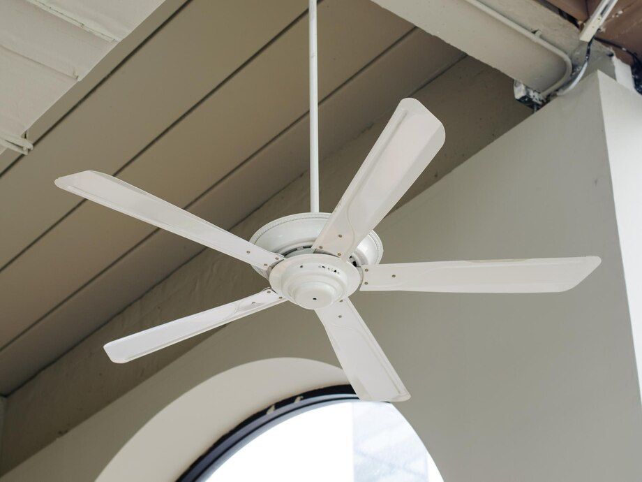 White ceiling fan mounted under a sloped roof indoors