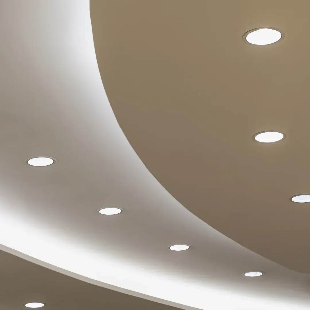 Curved modern ceiling with recessed round lights in white and beige tones