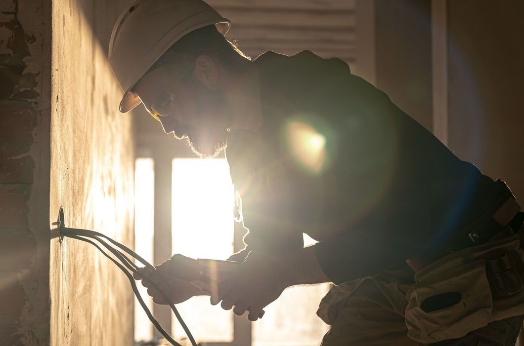 Construction worker in hard hat bending over with tools in a sunlit room