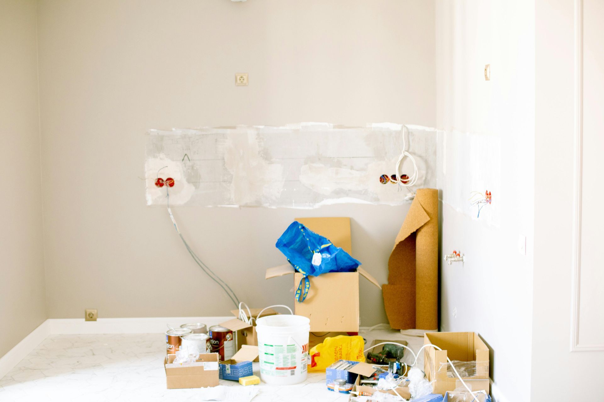 Electrician cutting wires, wearing a hard hat and safety glasses, inside a building.
