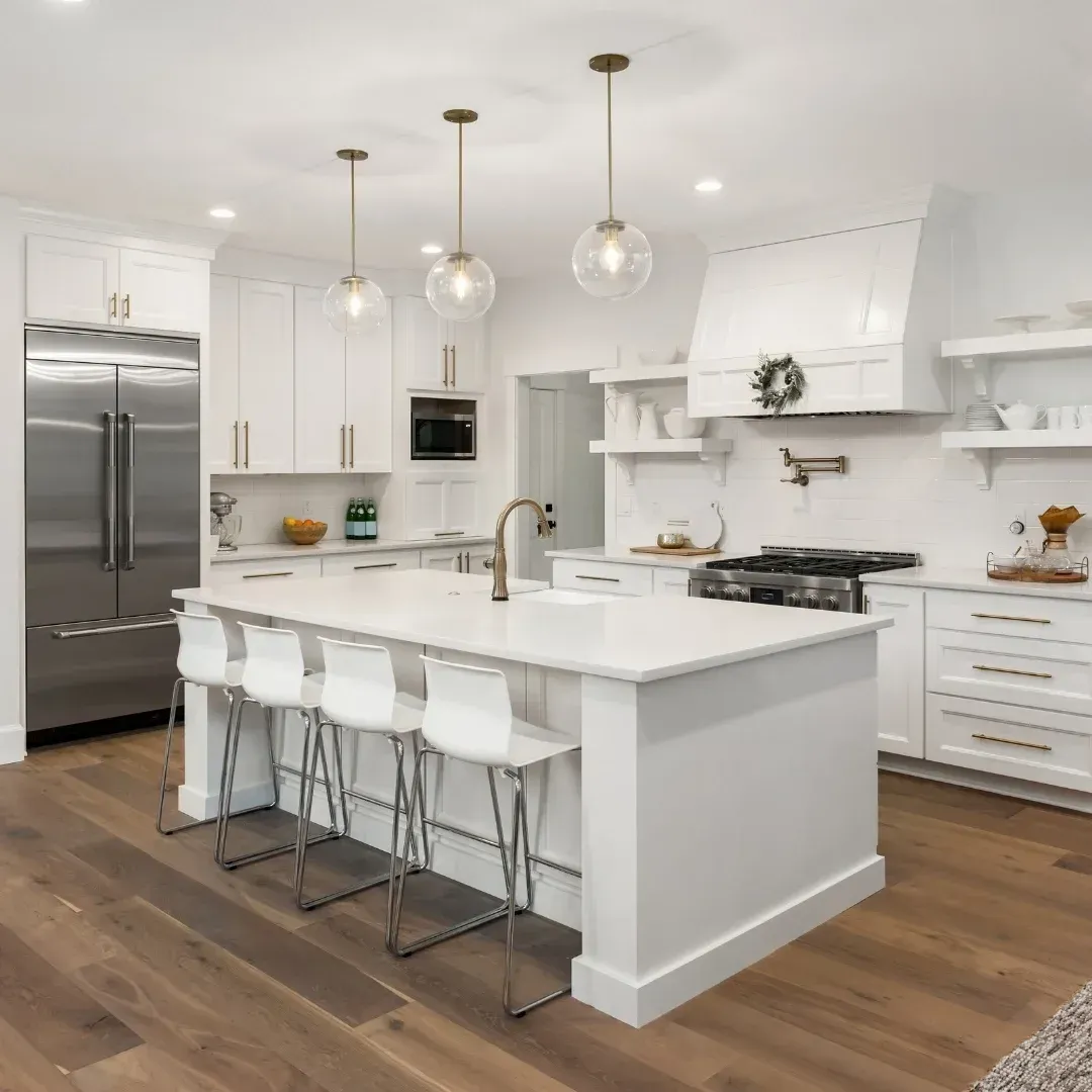 Modern white kitchen with island seating, stainless steel fridge, and LED lights