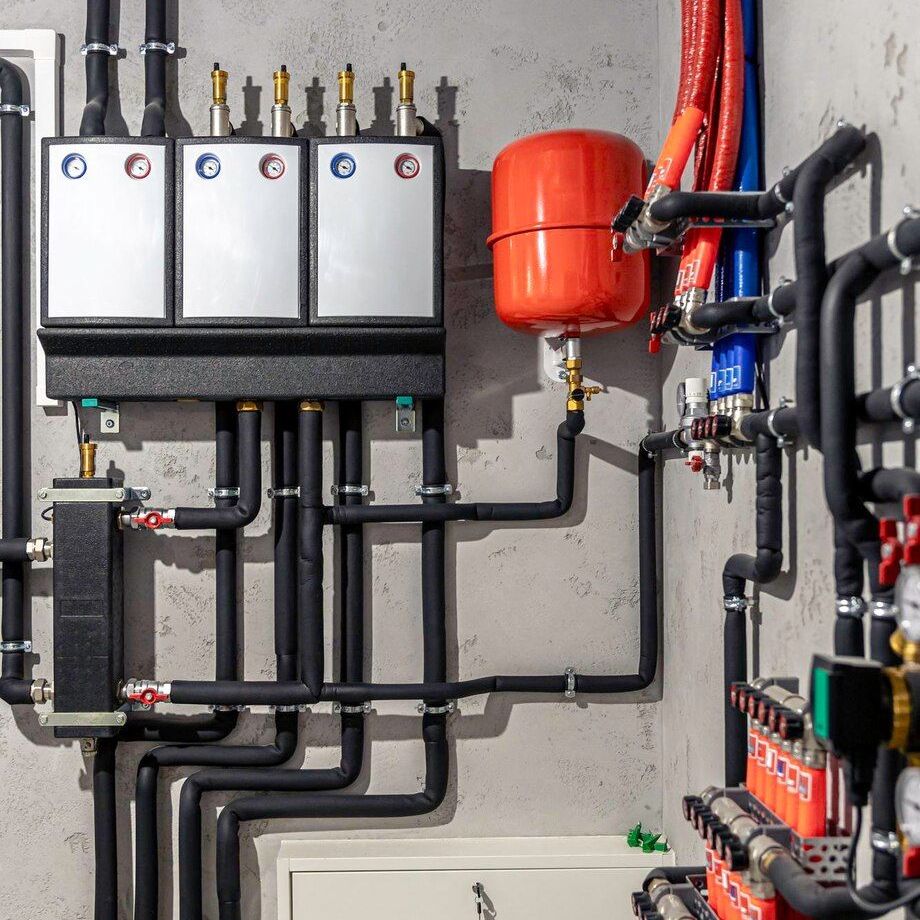 Wall-mounted plumbing and heating system with pipes, valves, tanks, and control units in a utility room.