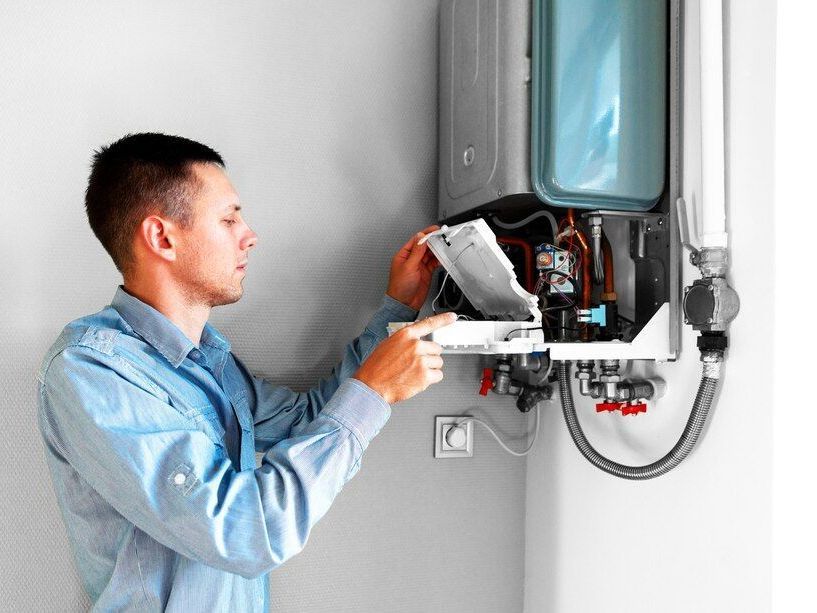 Technician inspecting an open wall-mounted boiler with tools in a home utility room