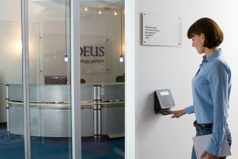 Woman using a wall-mounted keypad at a glass office entrance