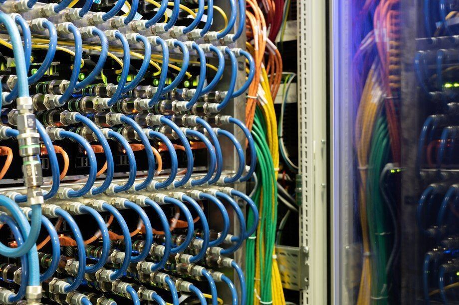 Blue, orange, and yellow cables connected in a server room.
