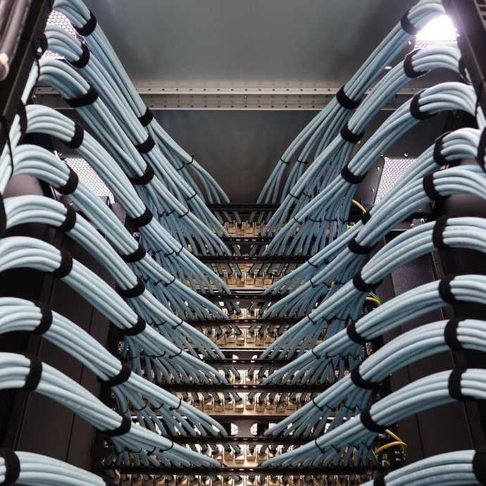 Blue network cables, bundled with black Velcro straps, neatly arranged in a server rack.