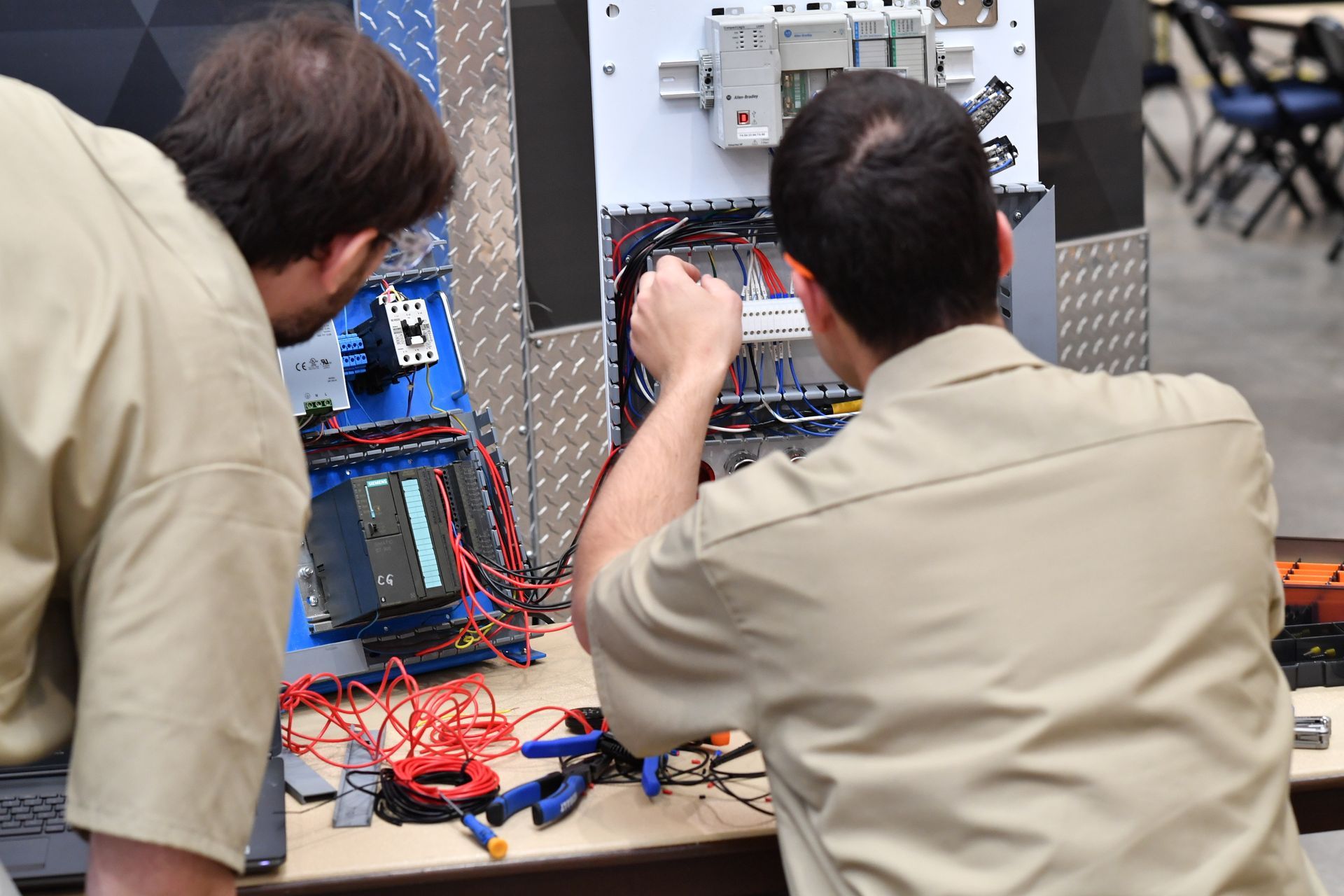 Two technicians working on an electrical control panel.