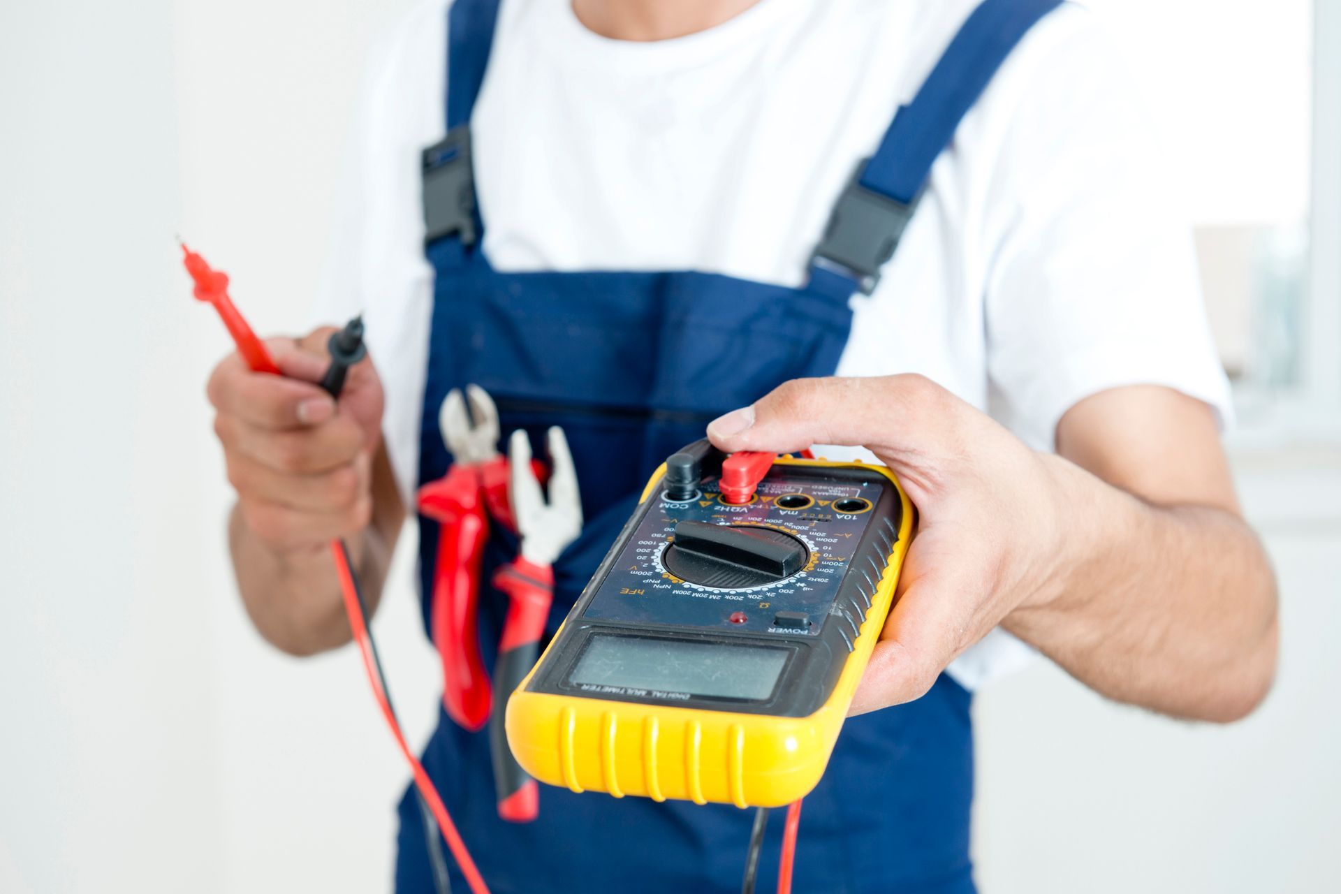 Electrician using multimeter during electrician training courses, holding tools and testing device. Electrician using multimeter during electrician training courses, holding tools and testing device.