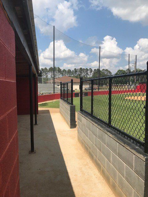 A walkway leading to a baseball field with a chain link fence