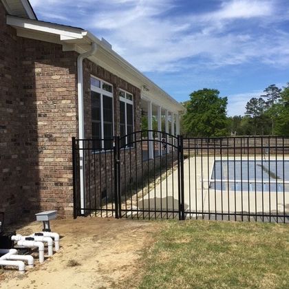 A brick house with a pool behind a metal fence
