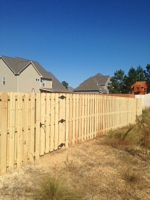 A worker is using a screwdriver on a fence installation.