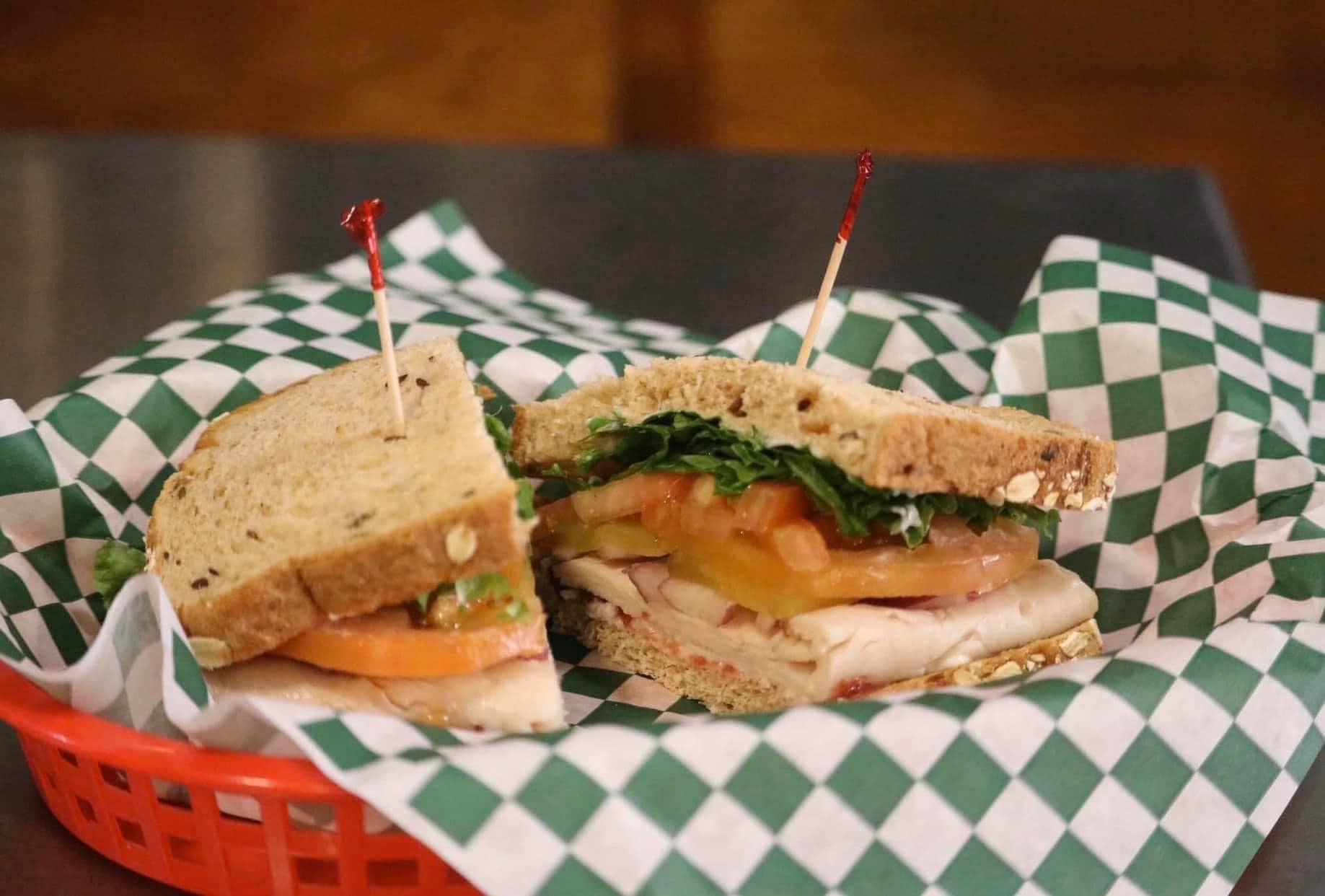 Sandwich cut in half on a tray with green-and-white checkered paper lining.