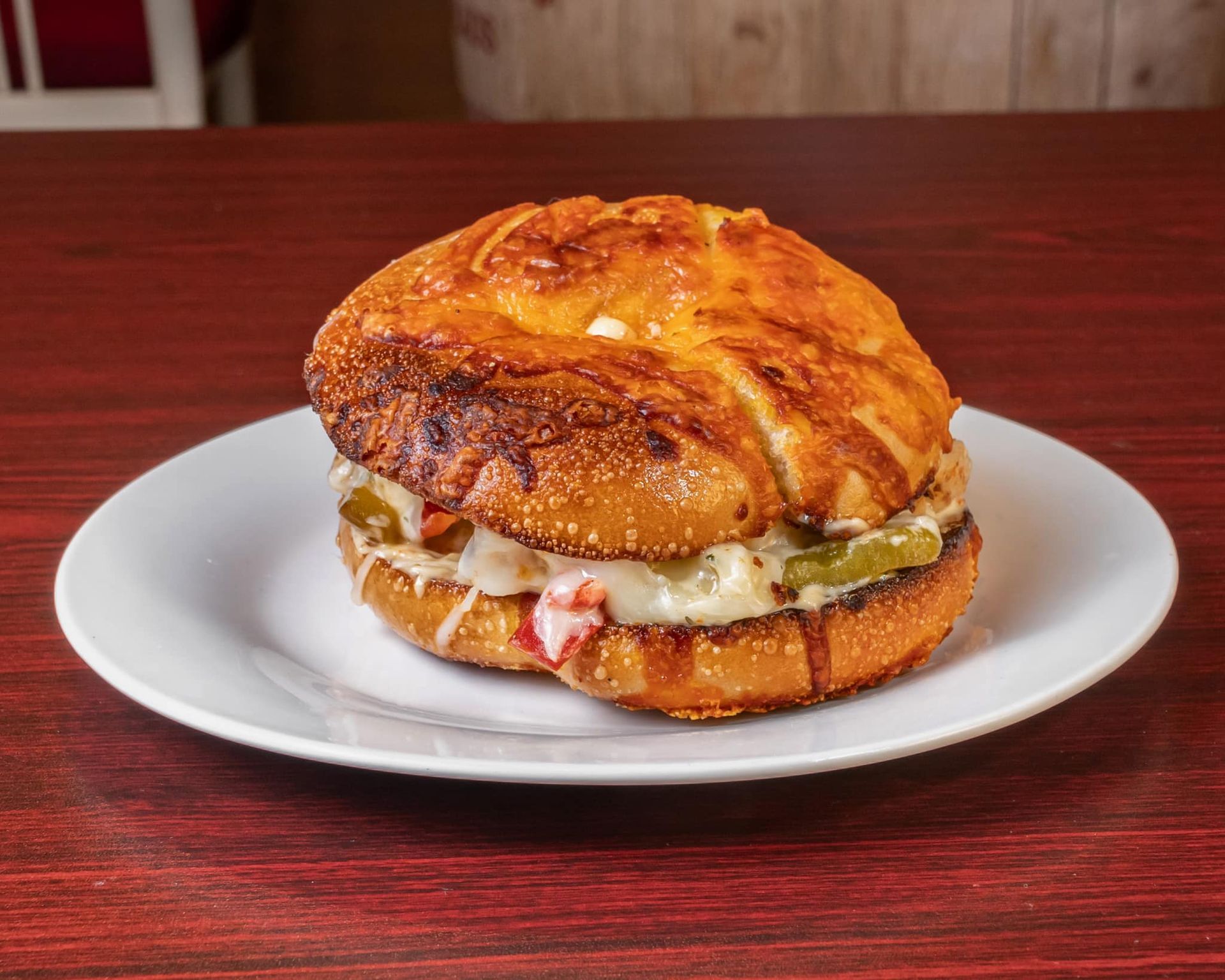 Sandwich with melted cheese on a white plate on a wooden table