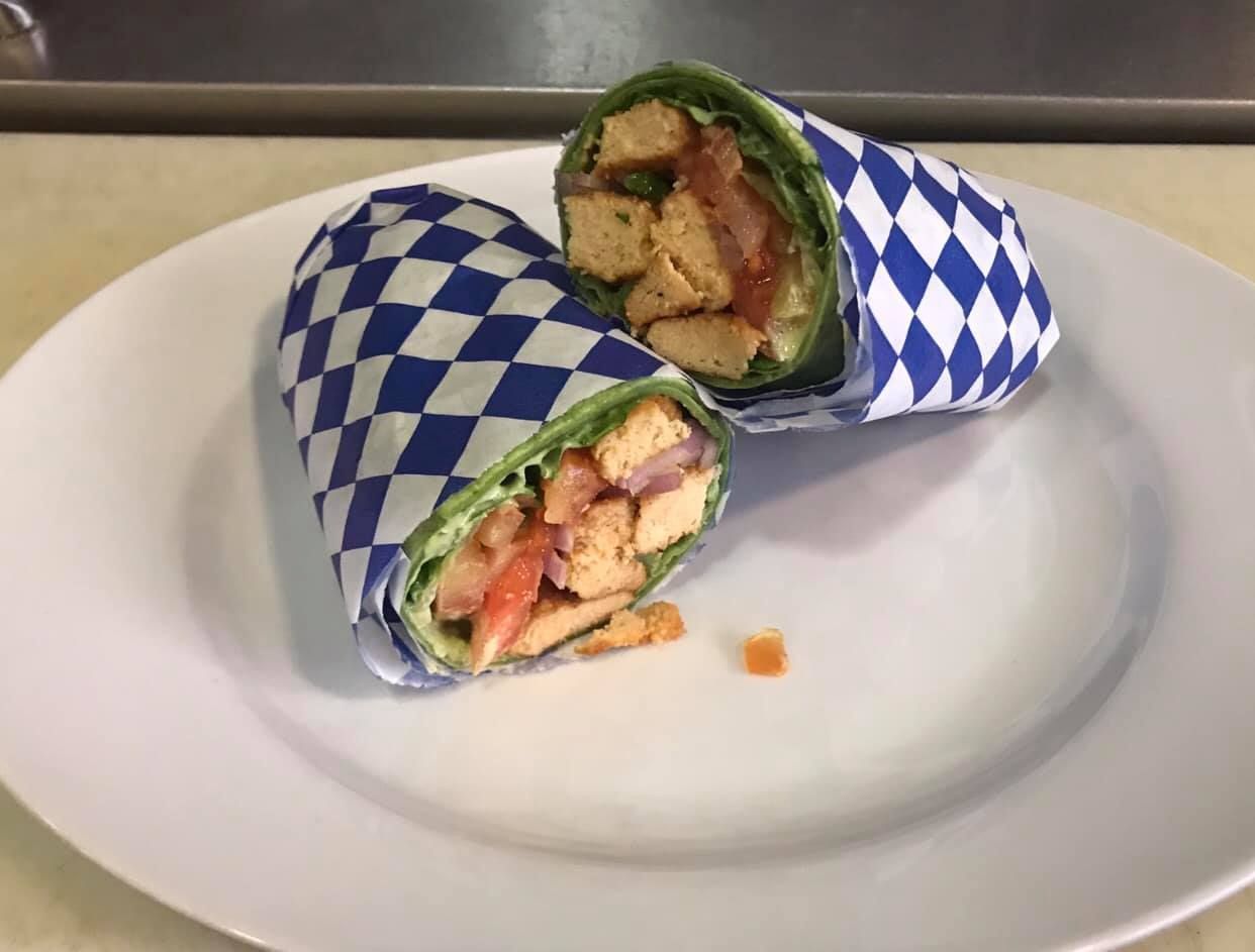 Halved wrap sandwich in blue-and-white checkered paper on a white plate