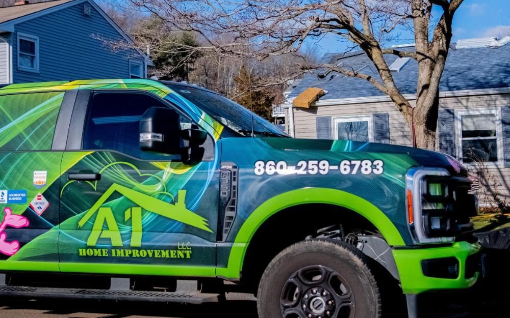 A green and blue truck is parked in front of a house.