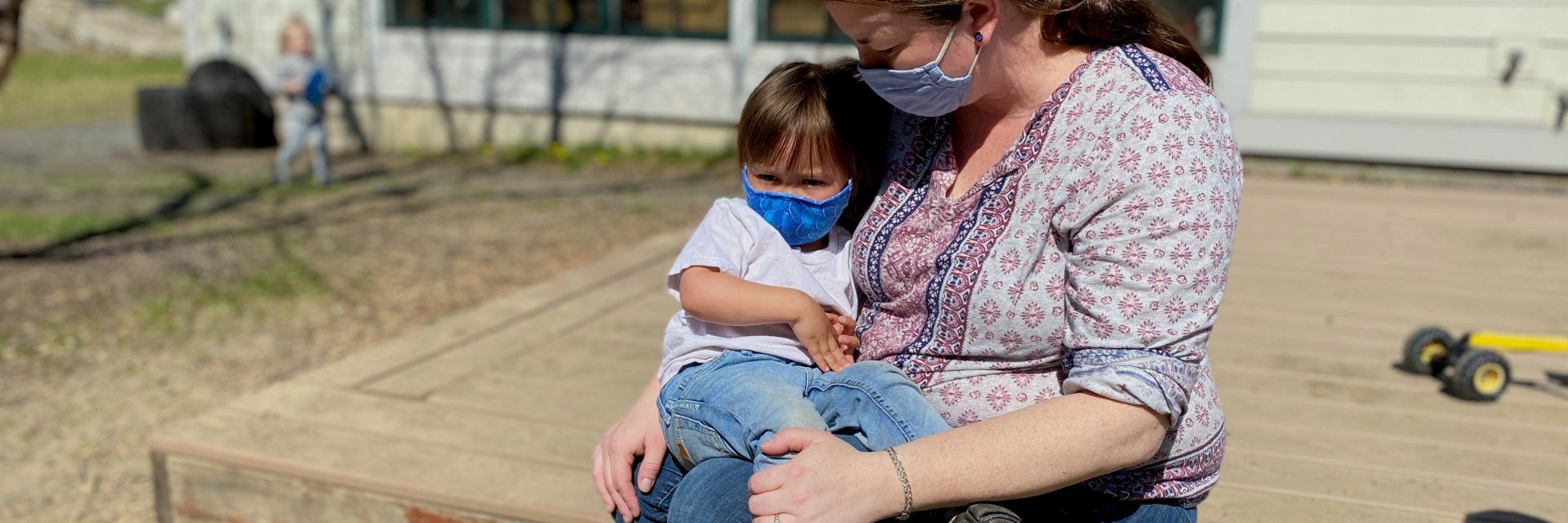 Guide sitting outdoors with a toddler on her lap