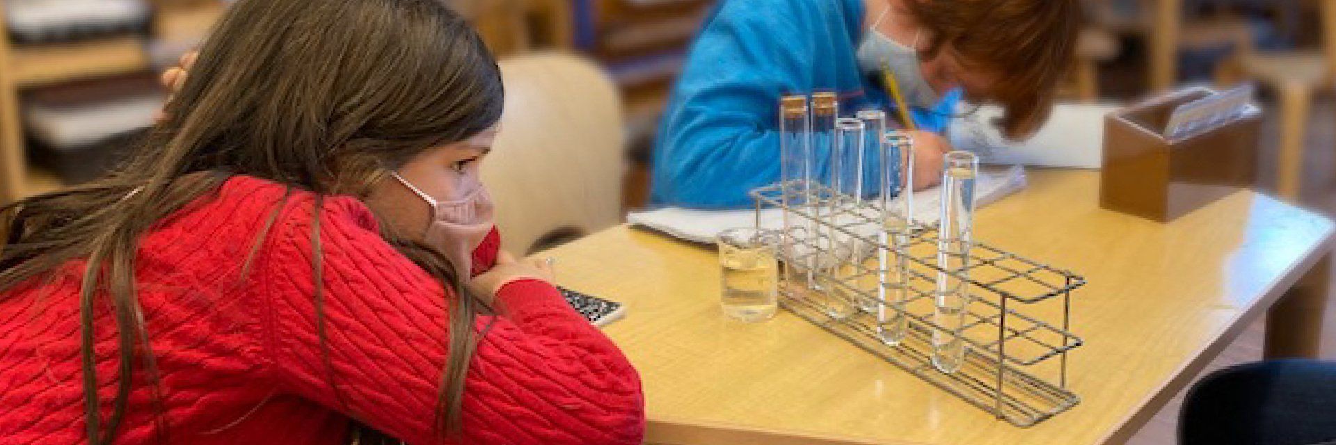 Two elementary aged children at a table with test tubes in a rack
