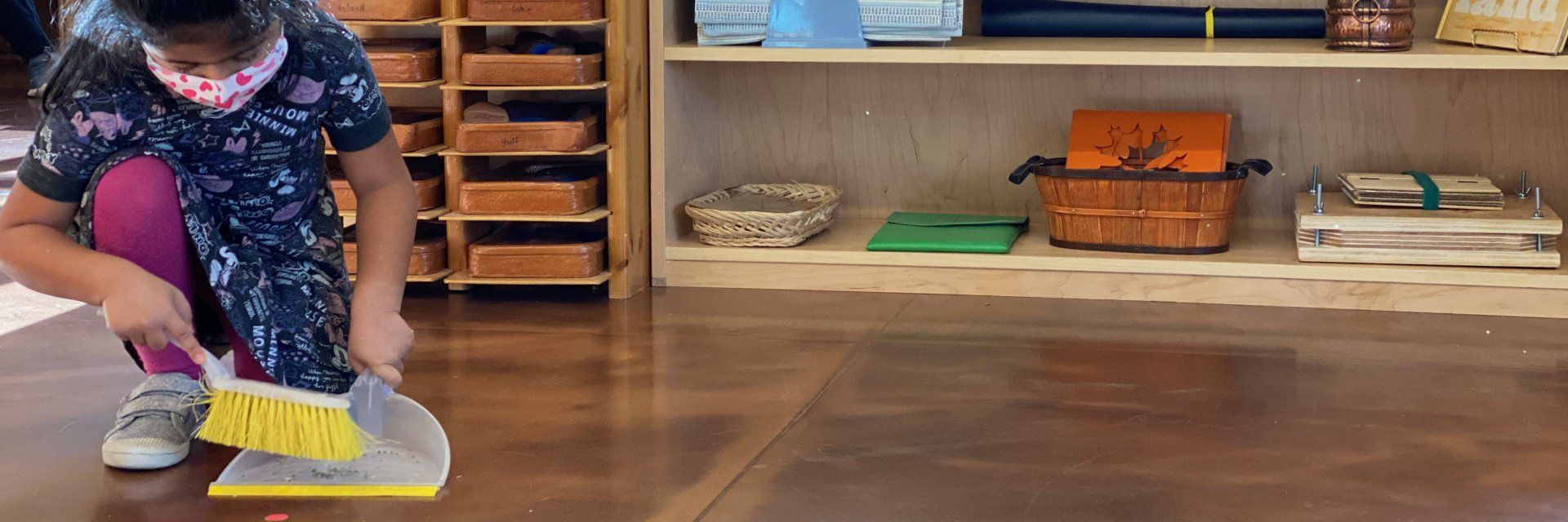 pre-school aged child sweeping the floor with dustpan and brush