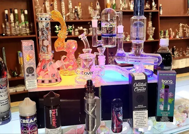 Colorful illuminated glassware and bottles displayed on a bar shelf with neon lighting