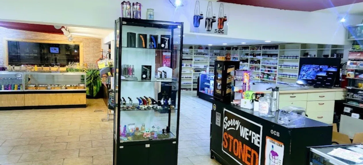 Bright convenience store interior with shelves, refrigerators, and a checkout counter displaying a hot items sign
