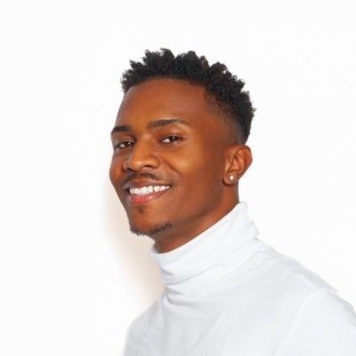 Smiling person in a white turtleneck against a plain white background