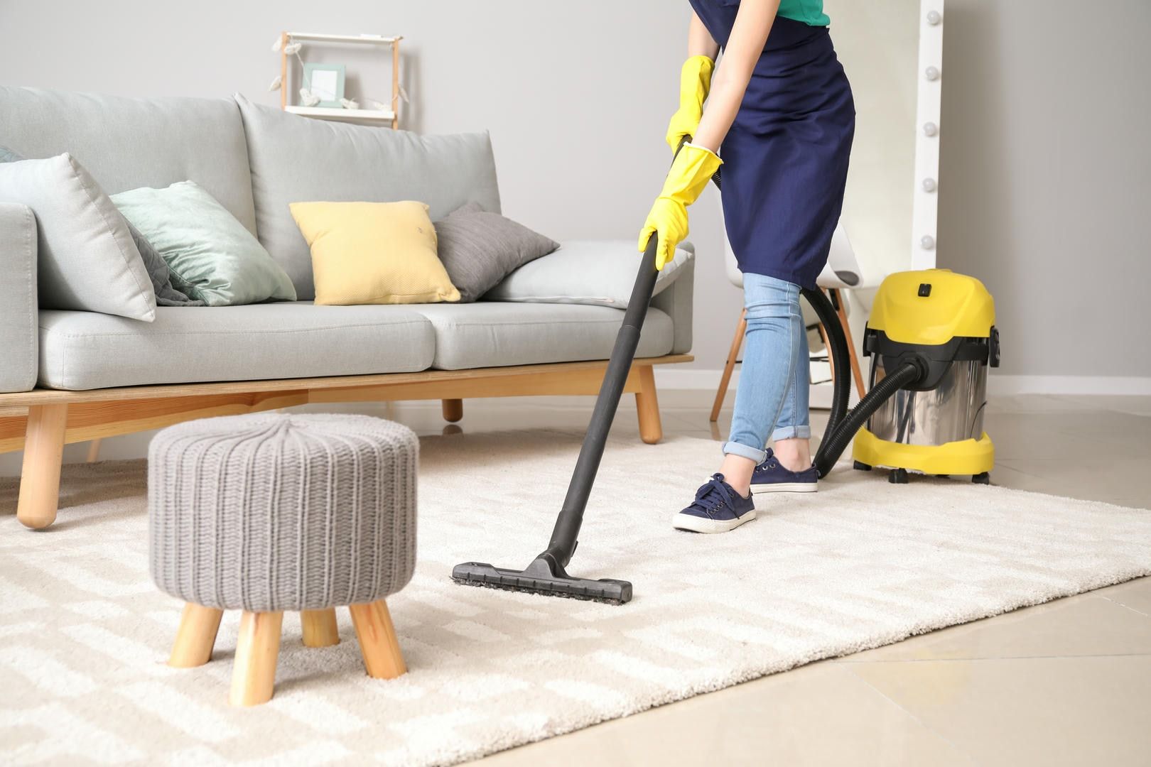 A woman is using a vacuum cleaner to clean a rug in a living room.